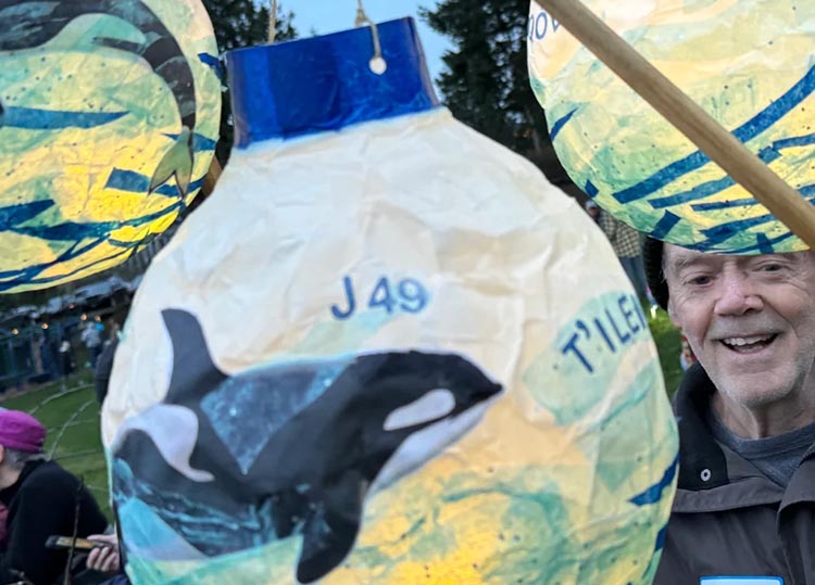 Man holding a luminary decorated with an orca